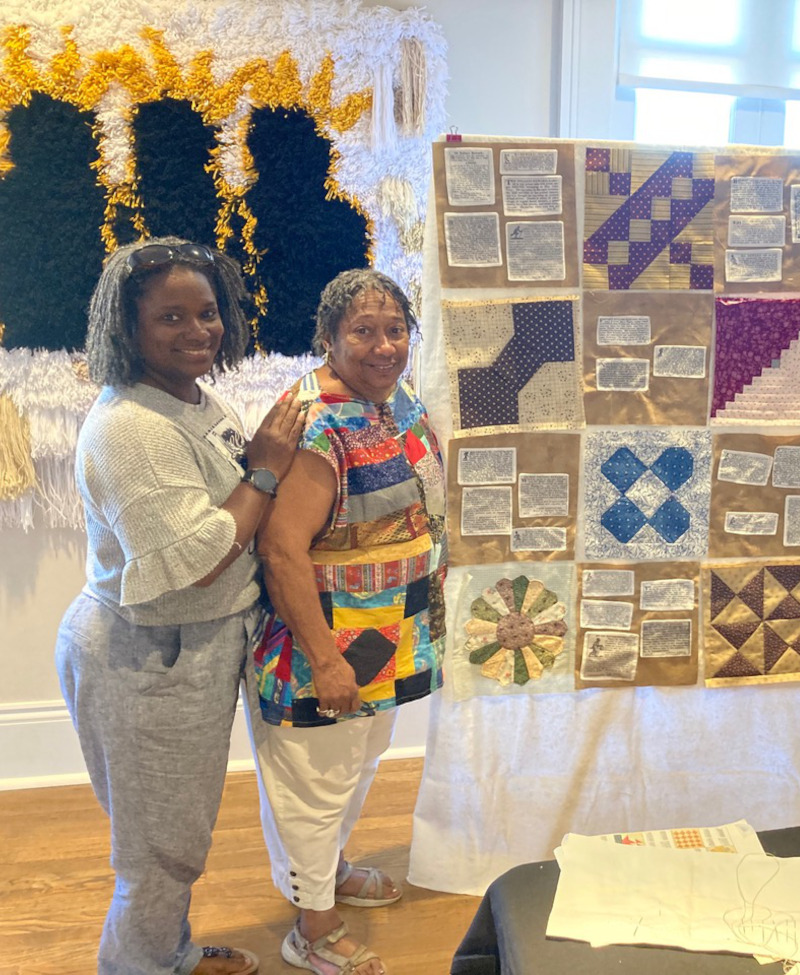 Two people standing next to quilt in progress