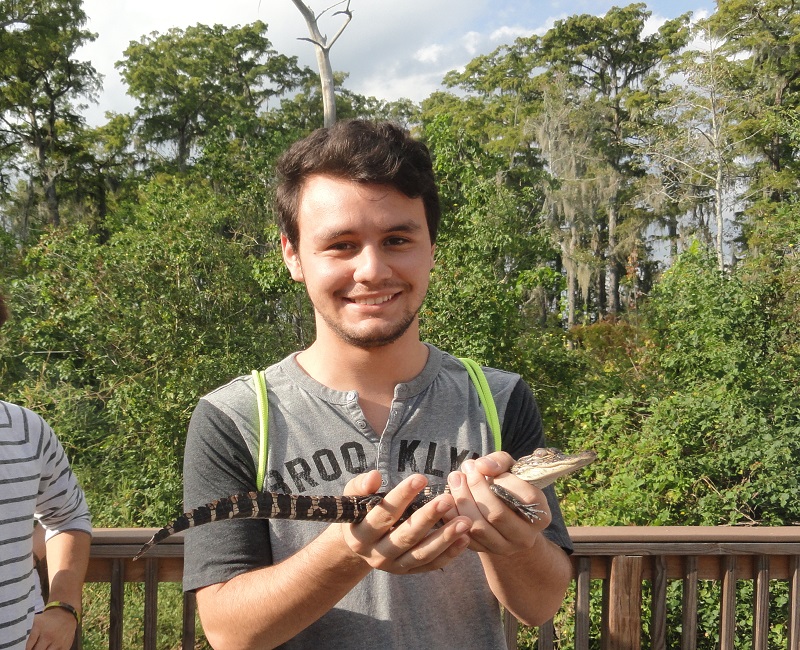Student holding baby alligator in the swamp