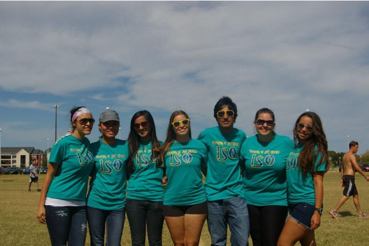 Students standing in a row holding arms and smiling.