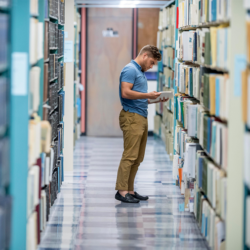 student in library looking at books