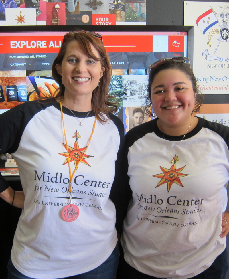 Two people wearing Midlo Center shirts stand in front of a YSOS display
