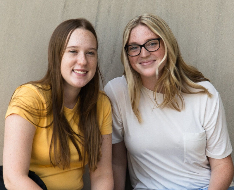 Two girls sitting by Earl K. Long library