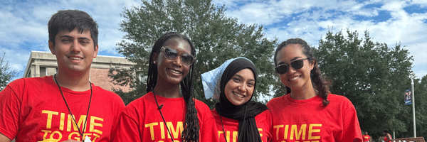 Image of four student ambassadors smiling and standing near each other at a campus event