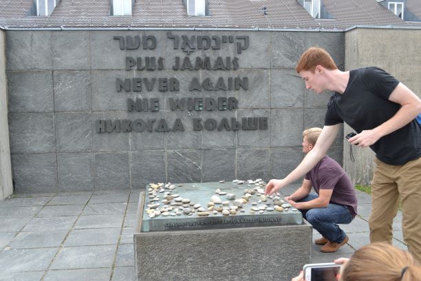 Student placing a stone on Dachau memorial