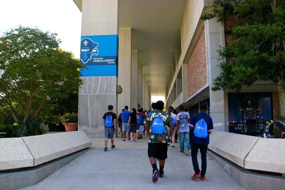 Students walking under Library Breezeway with UNO bags 