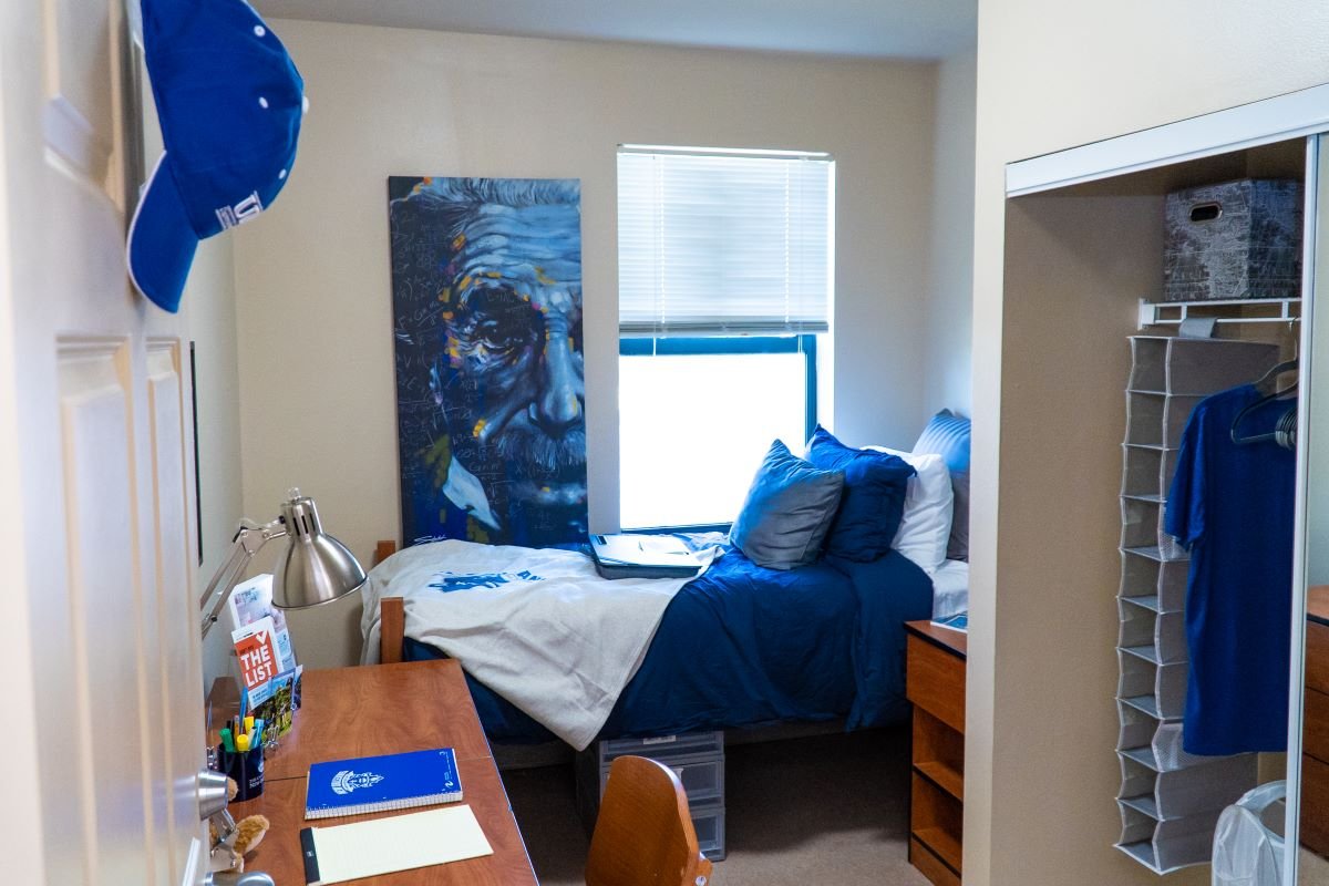 Image of interior of Pontchartrain Hall bedroom with bed and desk filled with UNO memorabilia. 