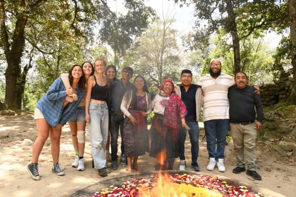 UNO students pose with their host family in front of a fire pit