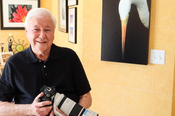 Photo of Frederick W. Thorne holding his camera beside one of his photos in a gallery