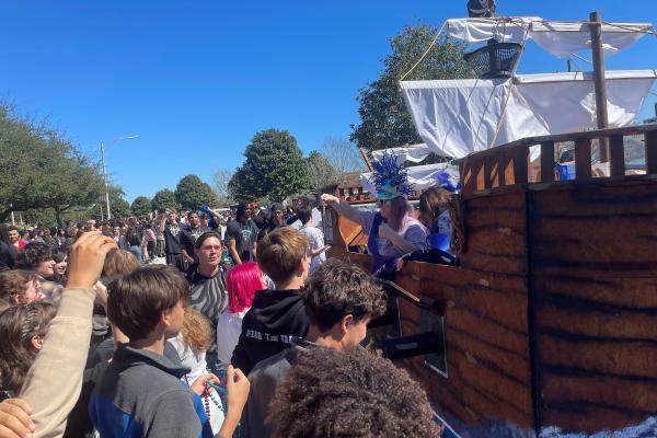 Students catch beads from a Krewe of UNO float