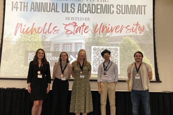 Five UNO students stand on stage at the 14th Annual ULS Academic Summit