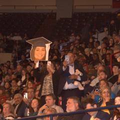 Parents at graduation hold up a sign of their daughter's face