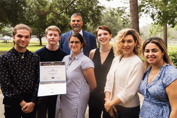 Members of the 2021 UNO Model United Nations club present President John Nicklow with copies of their awards from a competition earlier this year.