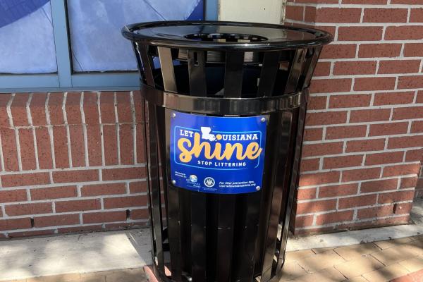 A photo of a trash can with the Let Louisiana Shine logo